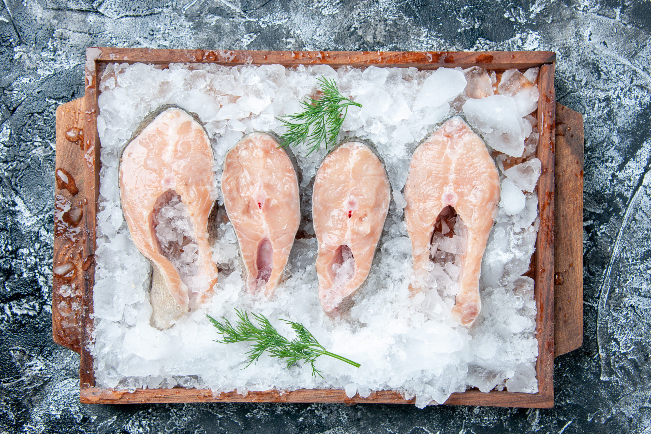 top-view-raw-fish-slices-with-ice-wood-board-table